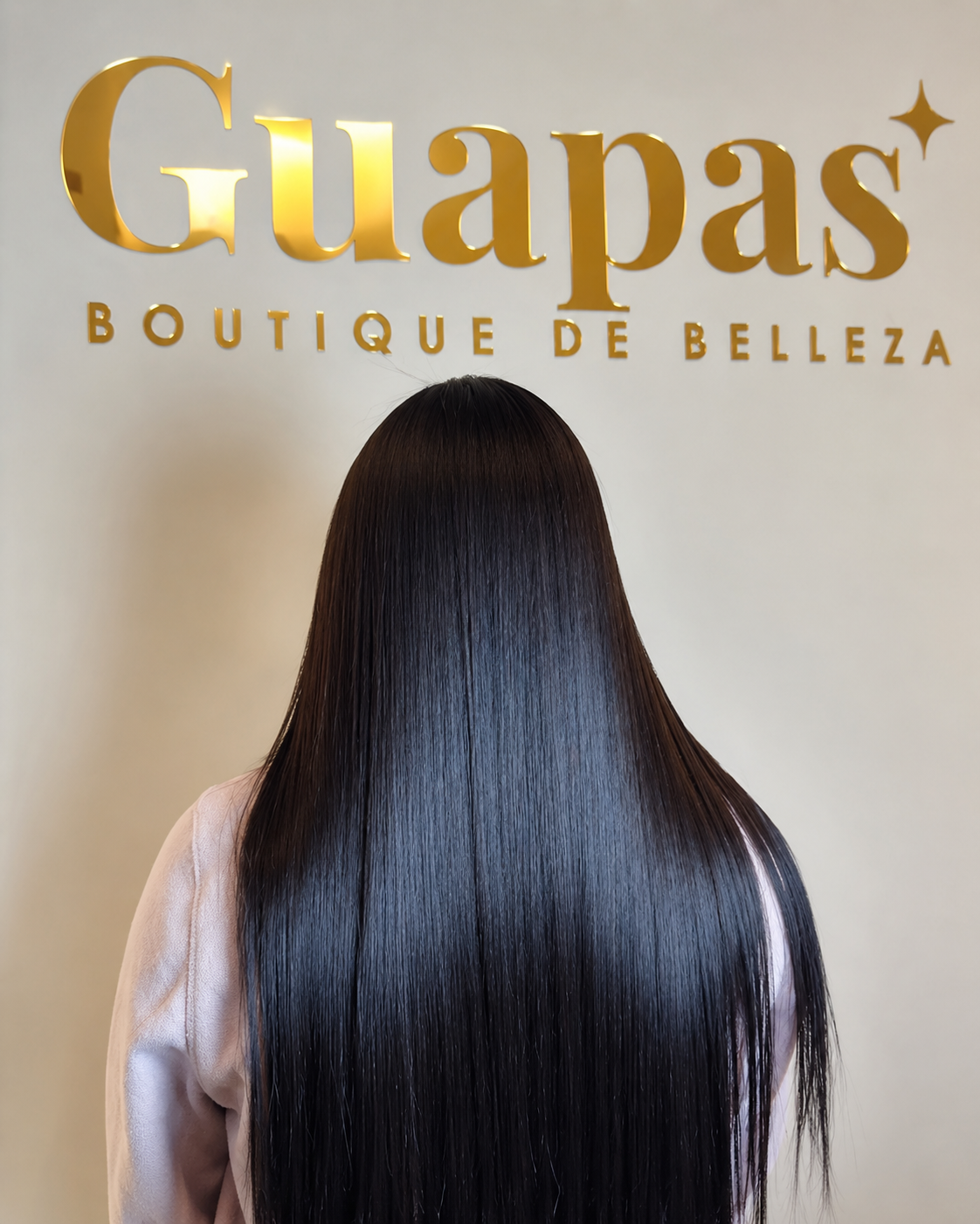 Clienta de Guapas con cabello largo y brillante frente al logo del salón
